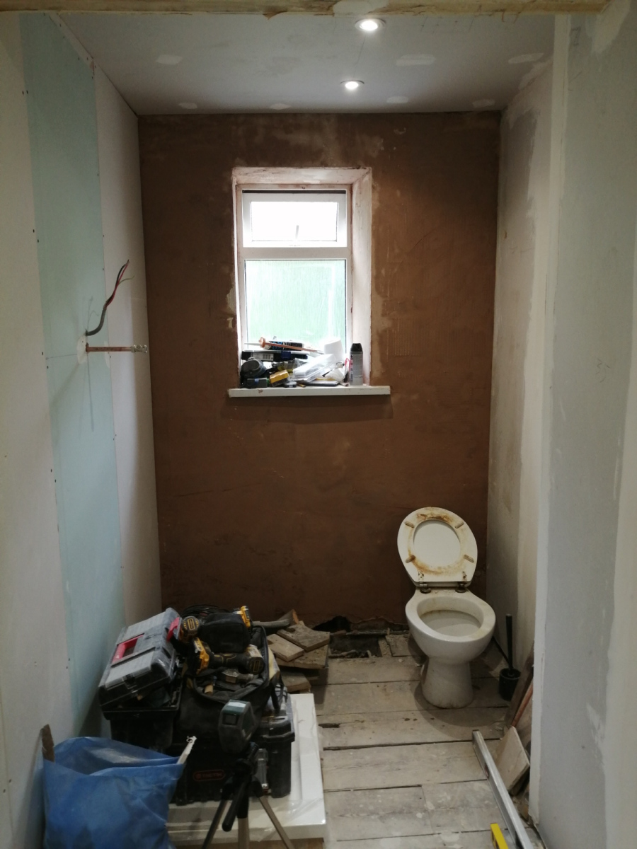 Long thin bathroom before work begins, with reinforced wall to support tiles