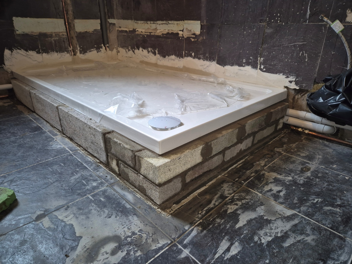 Stone block shower base pre-tiling with shower base installed on raised platform